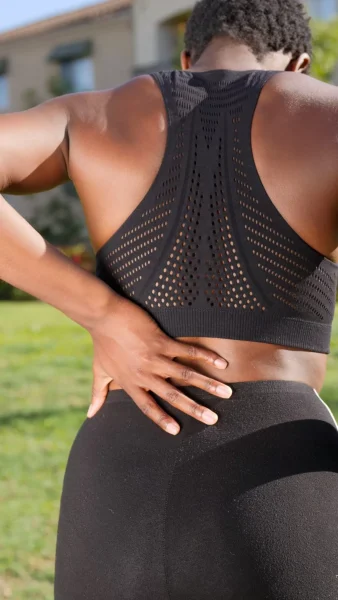 A woman in black workout suit suffering from back pain.