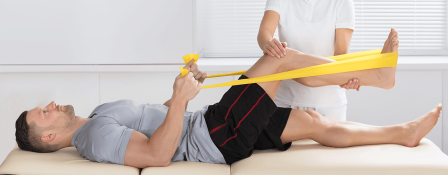 A man getting post knee surgery exercise with the help of a physiotherapist.