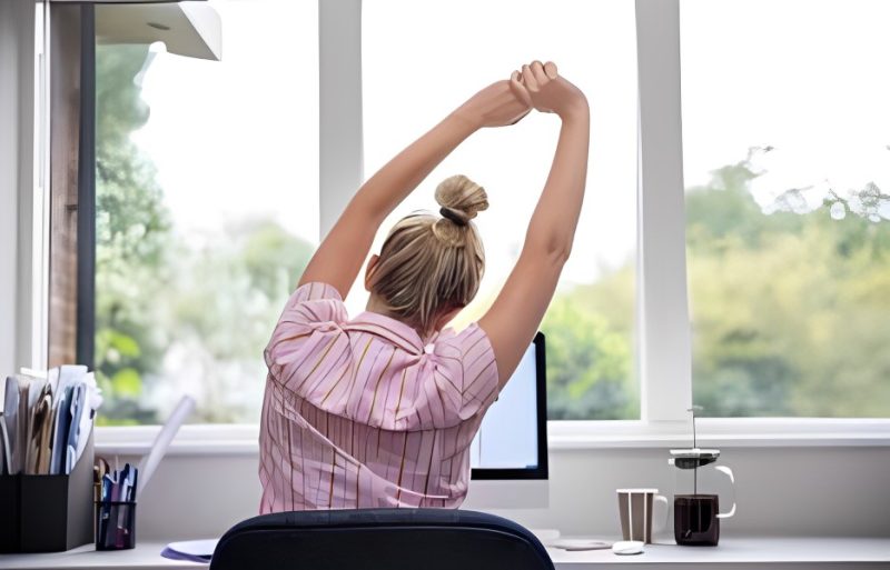 Woman stretching her body while working at her desk.