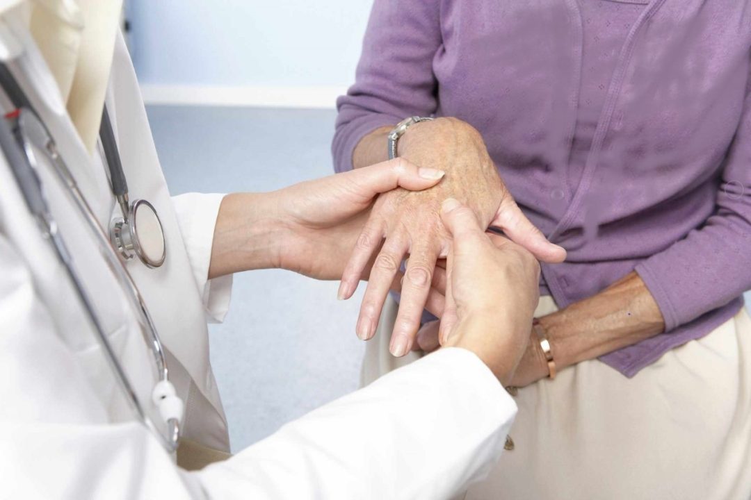 Doctor holding patient's hand and trying to diagnose her arthritis type.