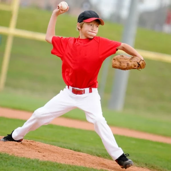 A young baseball player in red shirt shooting the ball.