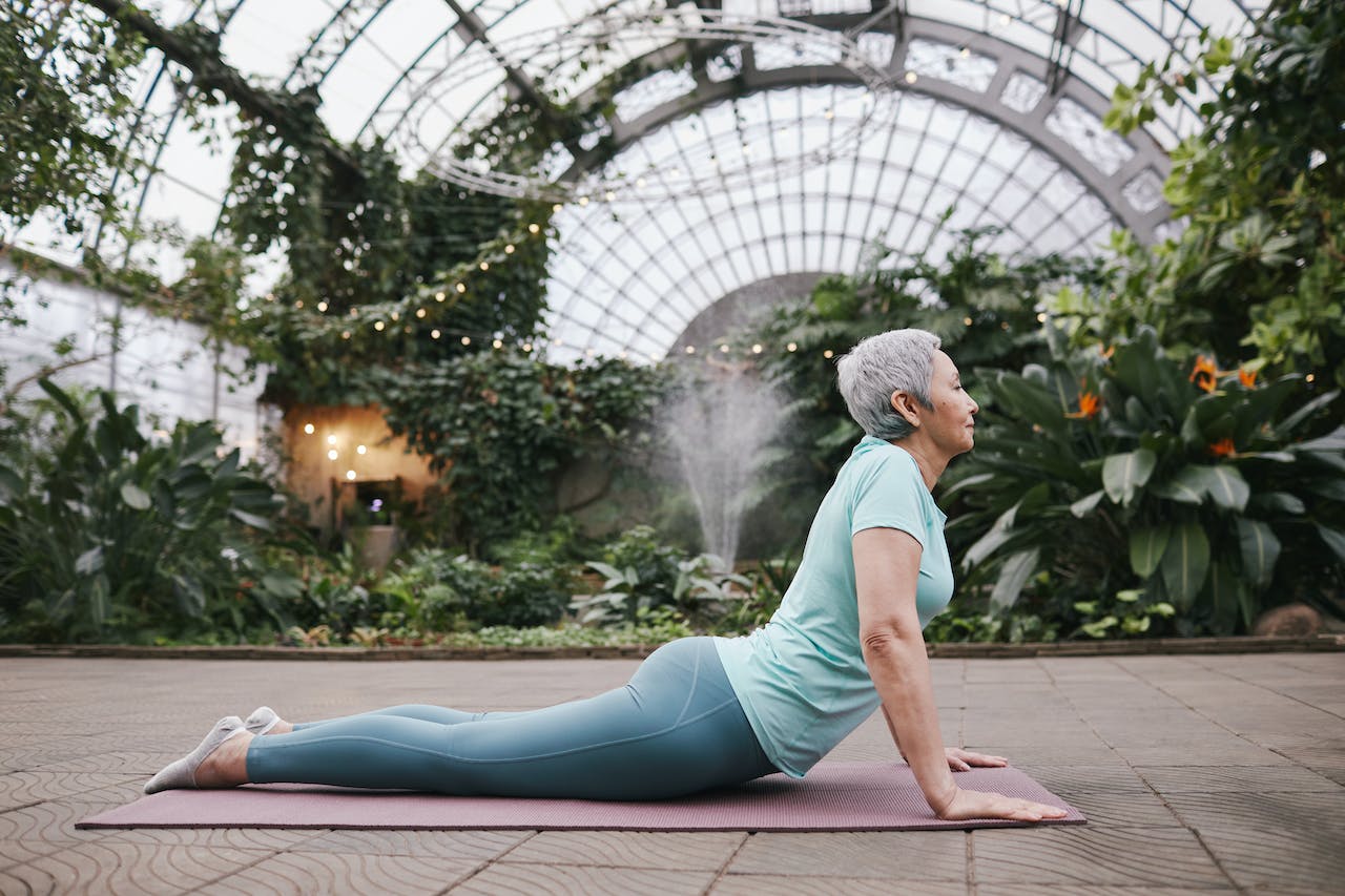 Old lady doing Yoga and stretching her body.
